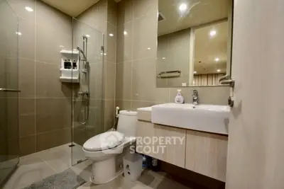 Modern bathroom with glass shower and sleek fixtures in contemporary apartment.