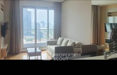 Modern living room with city view and balcony access in high-rise apartment.