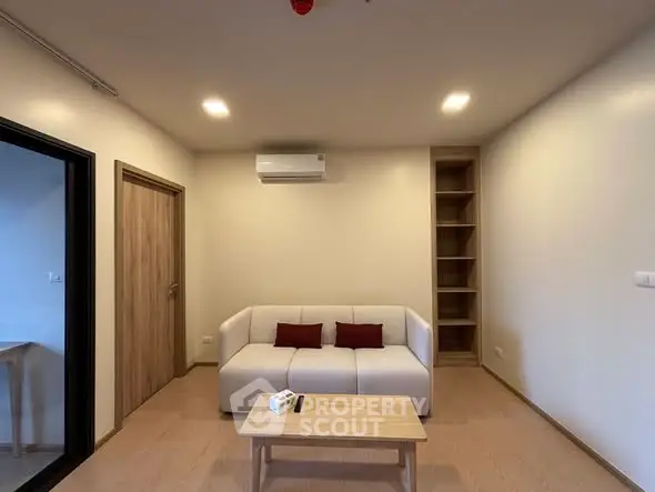 Modern living room with white sofa, wooden table, and built-in shelves, featuring minimalist design and cozy ambiance.