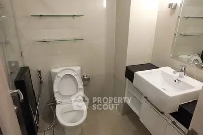 Modern bathroom with sleek fixtures and glass shelves in a contemporary apartment.