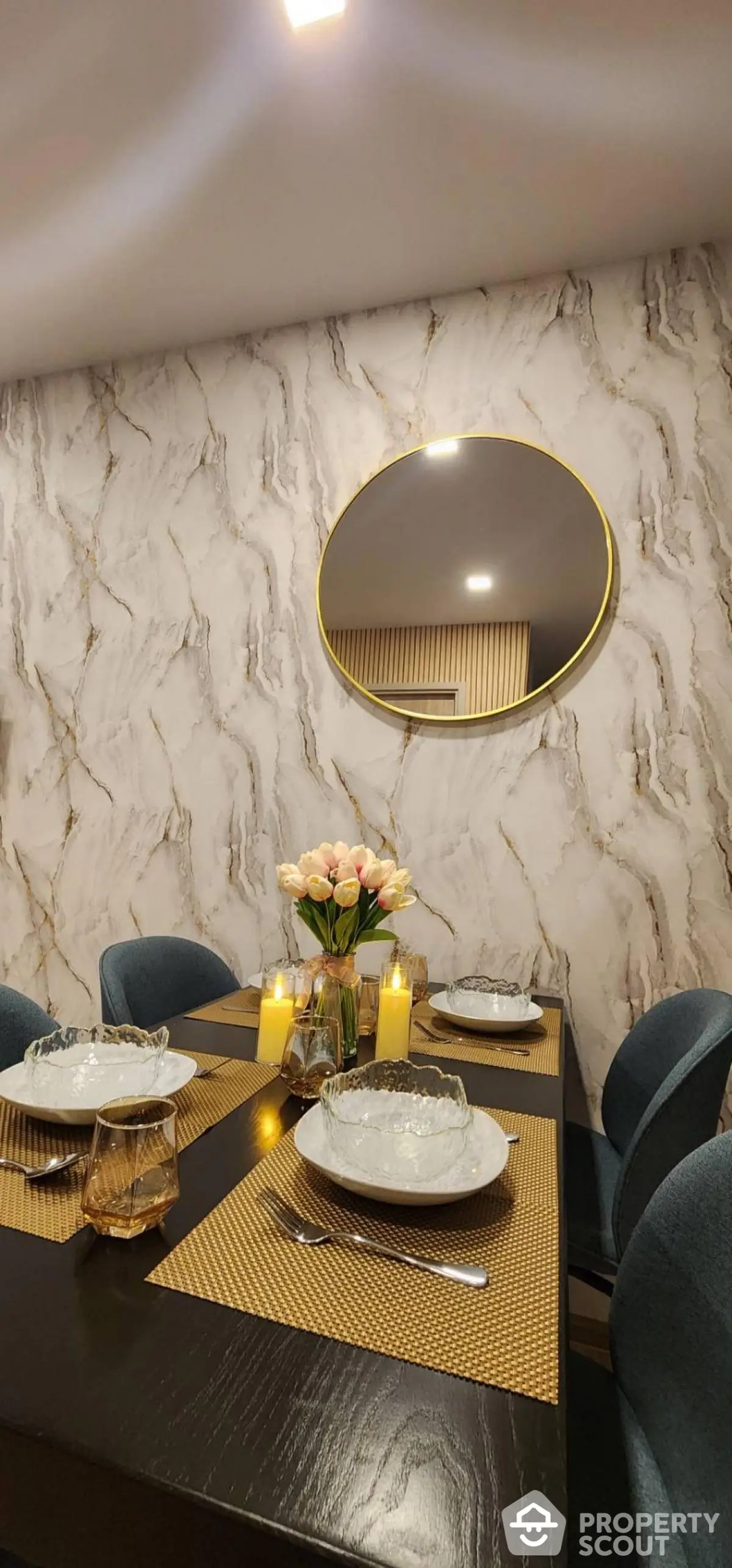 Elegant dining room with modern decor, featuring a round mirror and stylish table setting.