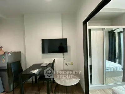 Modern apartment interior with dining area and wall-mounted TV, featuring sleek furniture and wooden flooring.