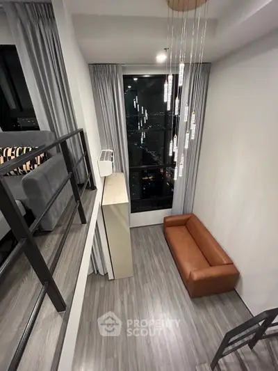 Modern loft apartment with high ceilings and large window offering city views.