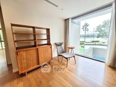 Spacious room with modern wooden furniture and large window overlooking garden view.