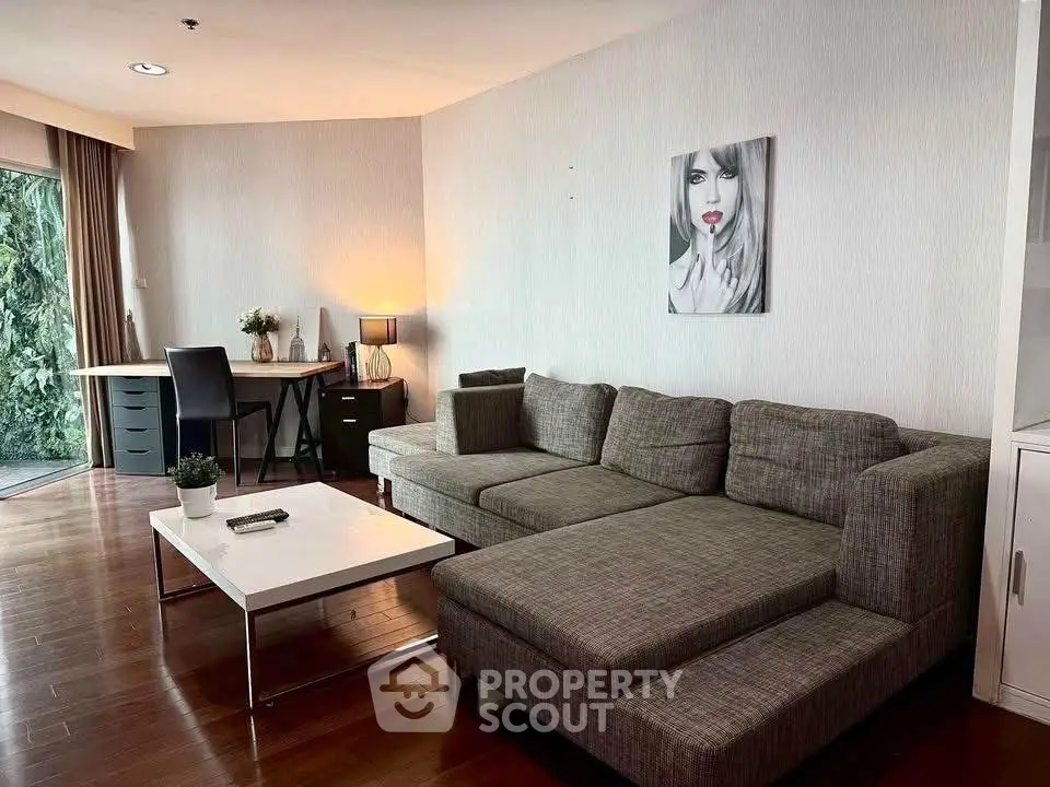 Modern living room with stylish gray sofa and workspace near large window.