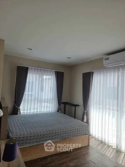 Bright and airy bedroom with large windows and modern decor, perfect for relaxation.