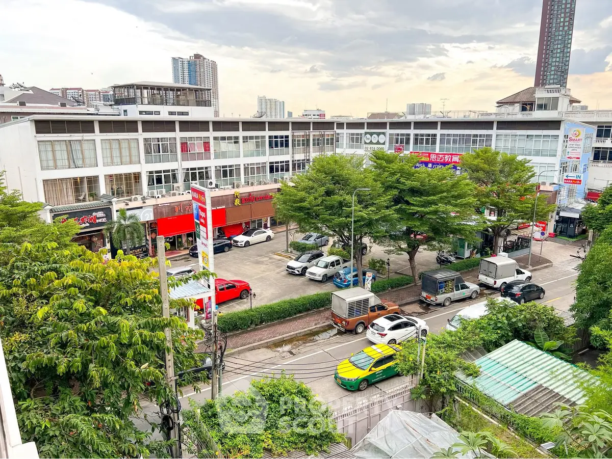 Vibrant urban street view with commercial buildings and lush greenery, ideal for business opportunities.