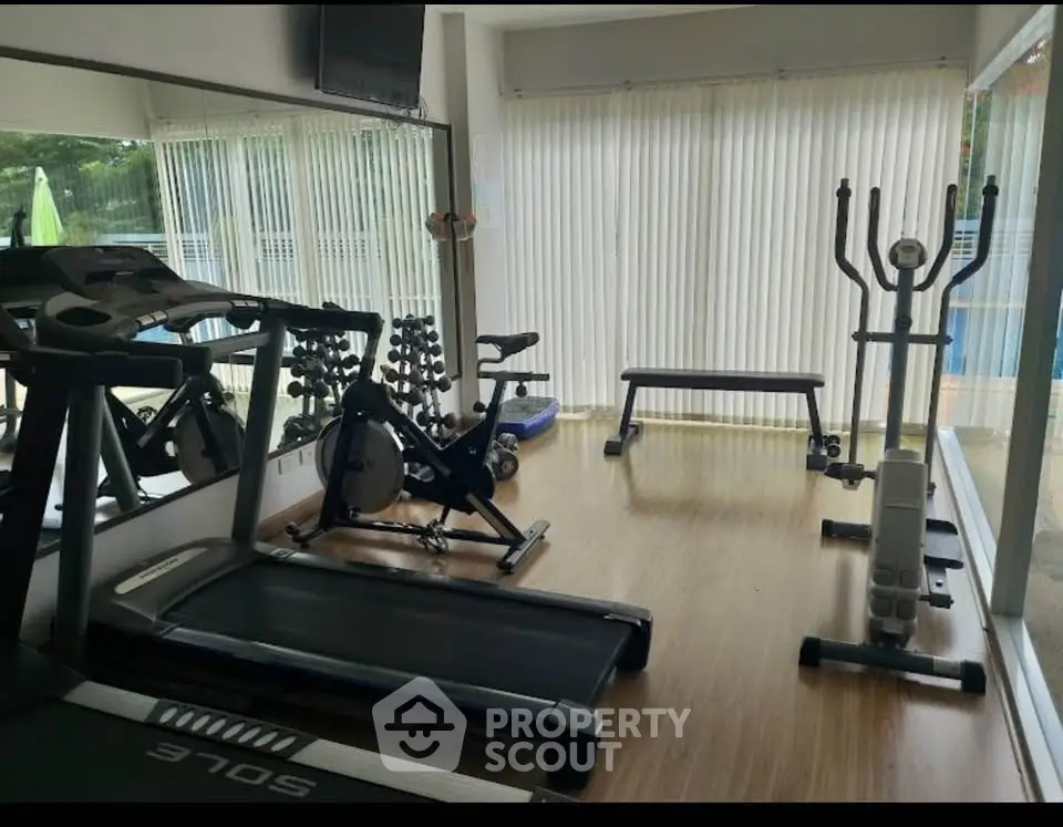 Modern home gym with treadmill, exercise bike, and elliptical in bright room.