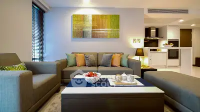 Modern living room with stylish decor and open kitchen layout, featuring cozy seating and contemporary artwork.