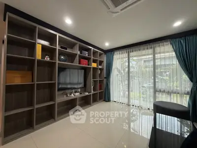 Spacious living room with modern shelving and large windows offering garden views.