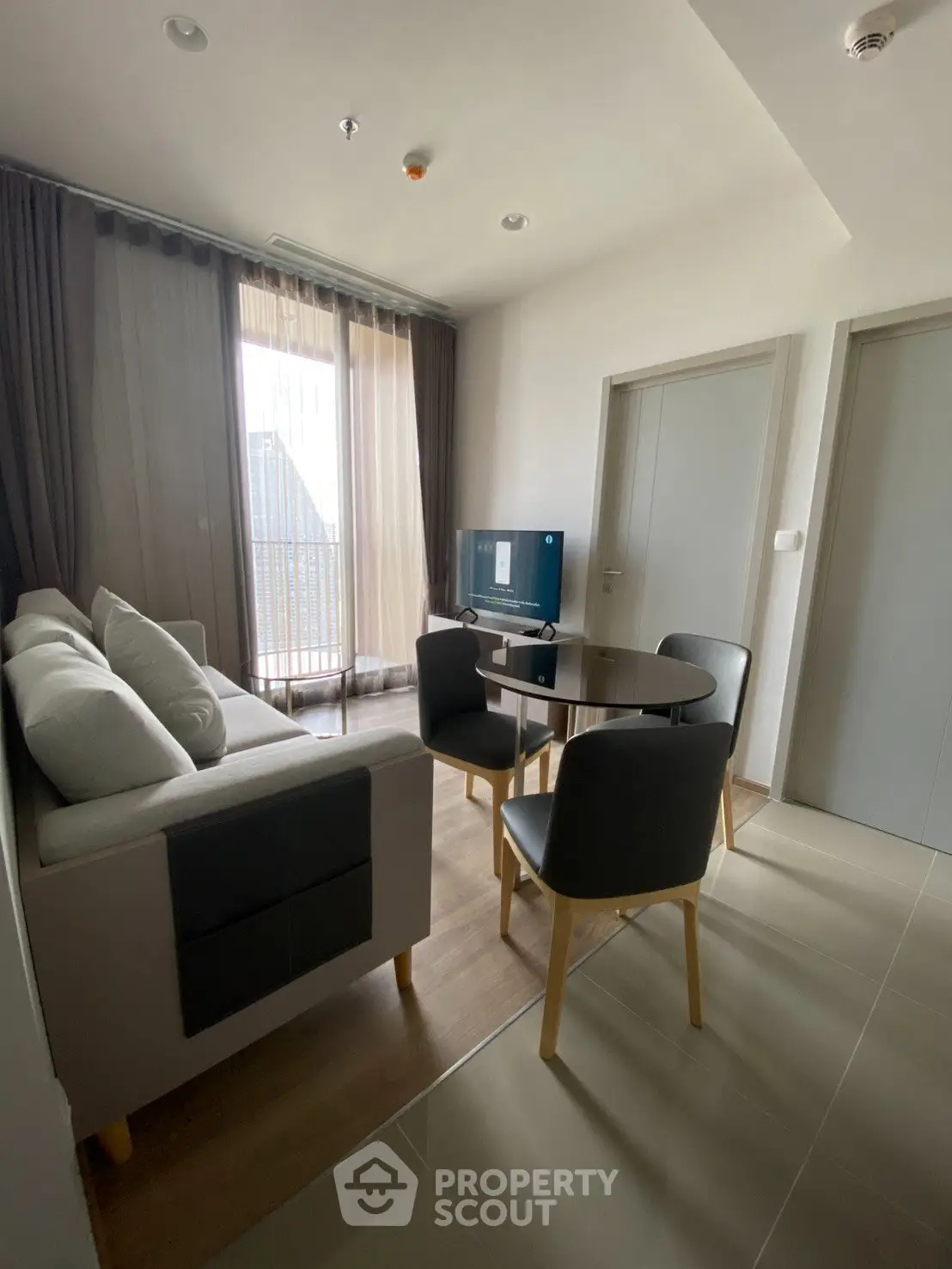 Modern living room with cozy sofa, round dining table, and balcony access in stylish apartment.