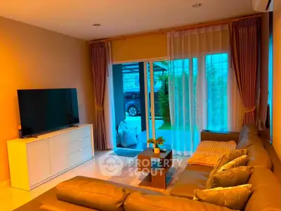 Spacious living room with modern decor and large TV, featuring a cozy sofa and elegant curtains.