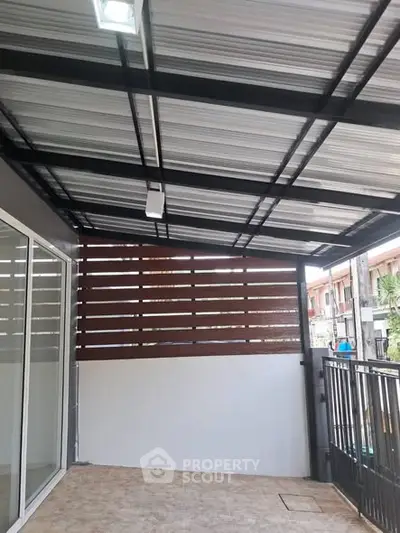 Modern covered balcony with metal roof and sliding glass doors