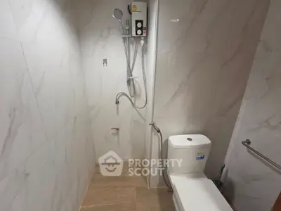 Modern bathroom with shower and toilet in sleek marble design.