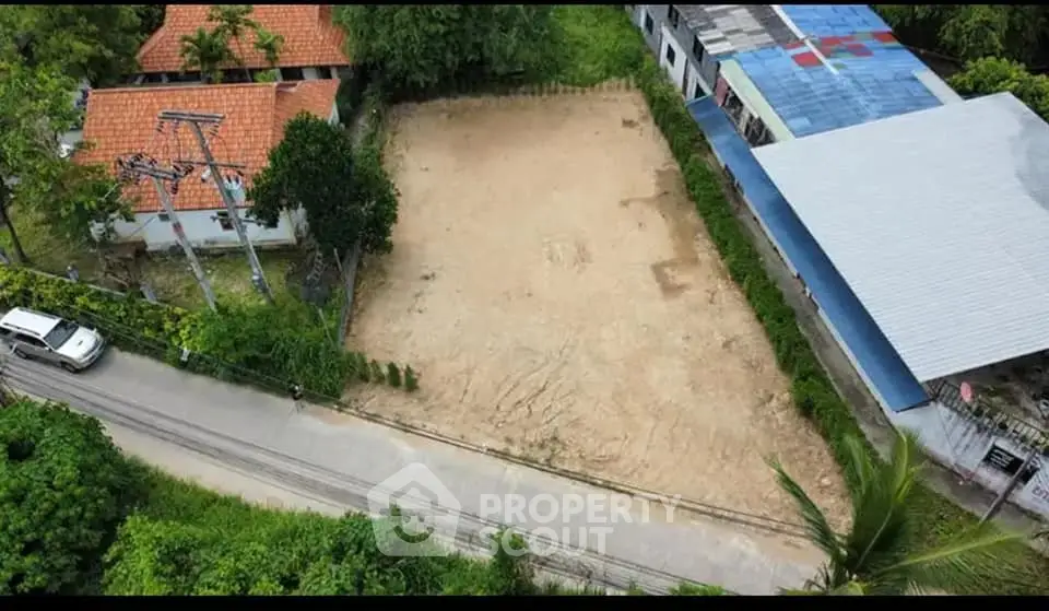 Prime vacant land parcel ready for development, surrounded by lush greenery and existing structures, ideal for a custom residential or commercial project.