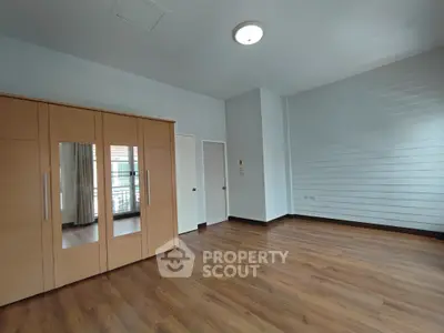 Spacious bedroom with wooden flooring and built-in wardrobe in modern apartment