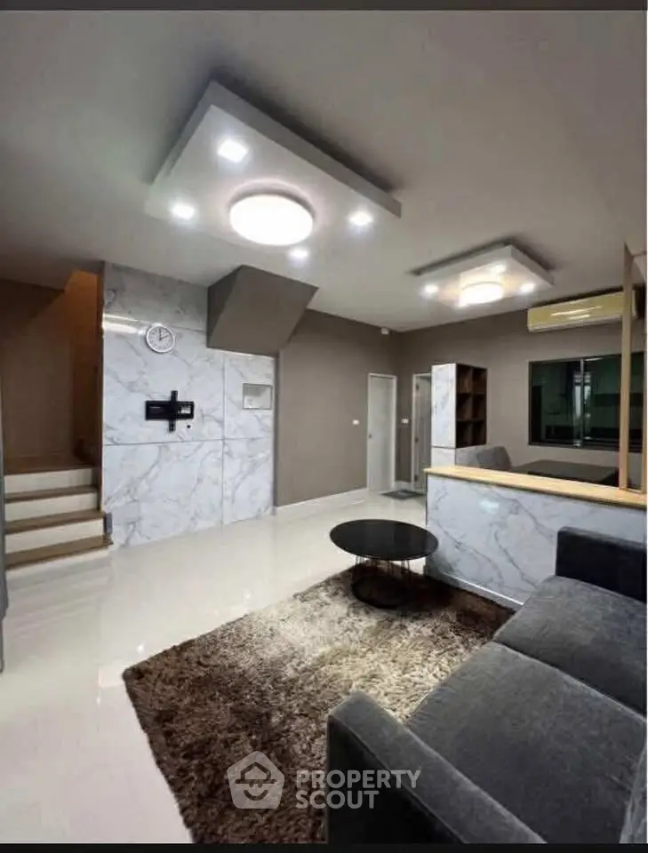 Modern living room with sleek design, marble accents, and cozy seating area.