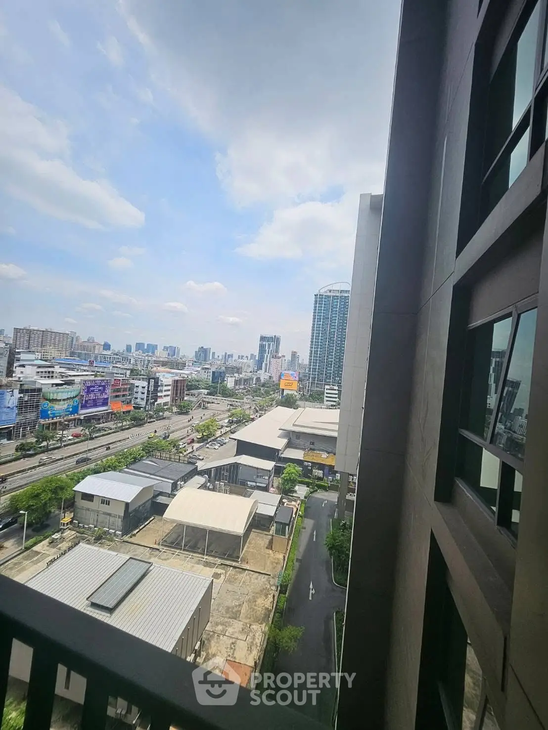 Stunning cityscape view from a high-rise building balcony, showcasing urban skyline and clear blue skies.