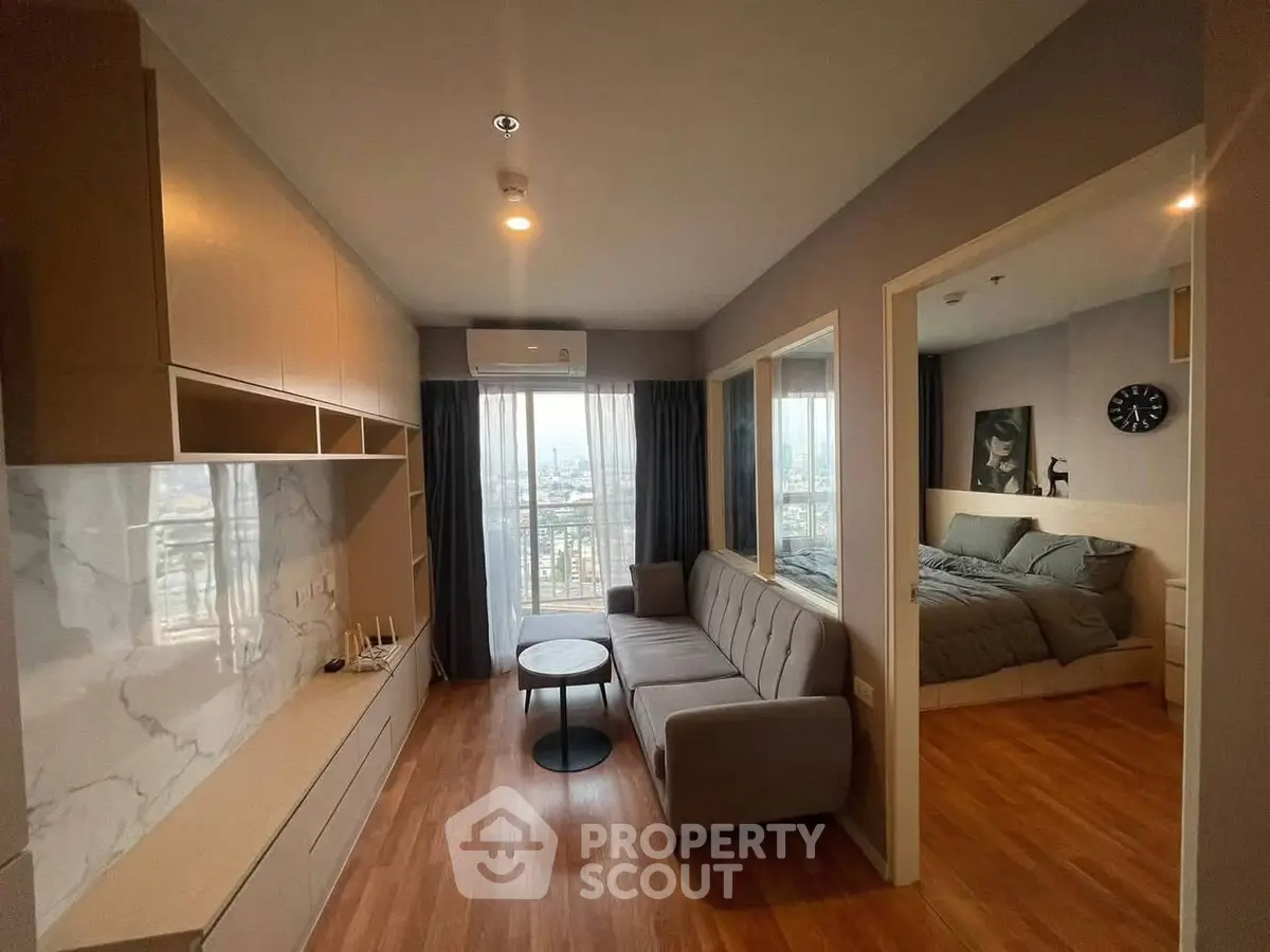 Modern apartment with open living room and bedroom, featuring wooden floors and city view.