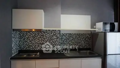 Modern kitchen with sleek design, featuring mosaic backsplash and stainless steel appliances.