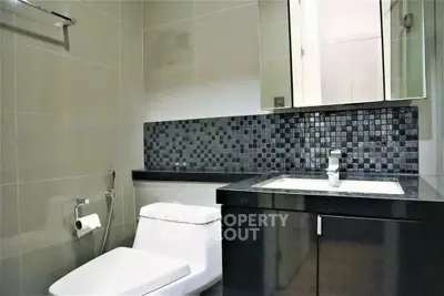 Modern bathroom with sleek design and stylish black tile accents.