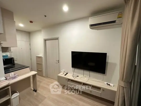 Modern living room with wall-mounted TV and air conditioning in a cozy apartment.