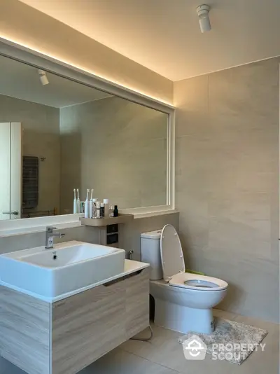 Modern bathroom with sleek fixtures and large mirror in a stylish home.