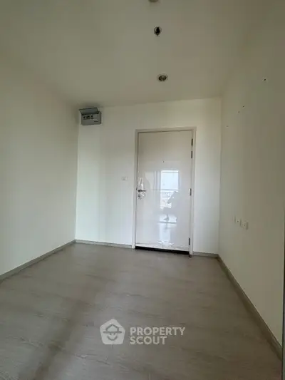 Minimalist empty room with wooden flooring and white walls, perfect for customization.