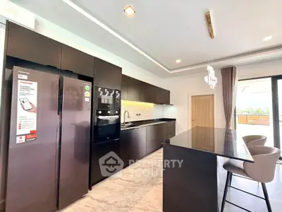Modern kitchen with sleek black cabinets, island, and built-in appliances in a bright open layout.