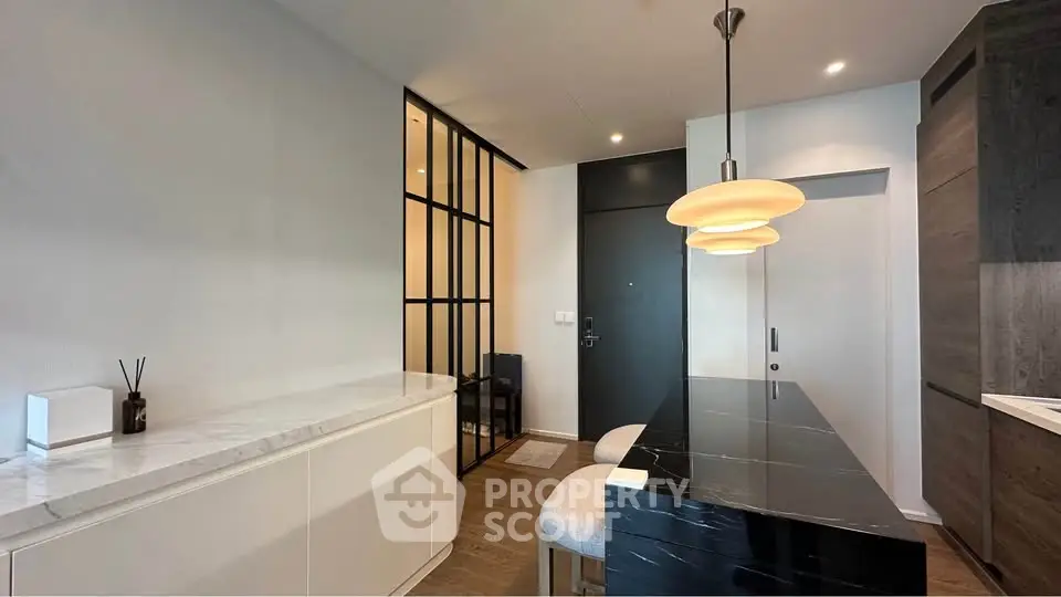 Modern kitchen with sleek black countertop and stylish pendant lights in a contemporary apartment.