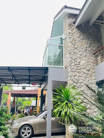 Modern stone facade house with carport and lush greenery