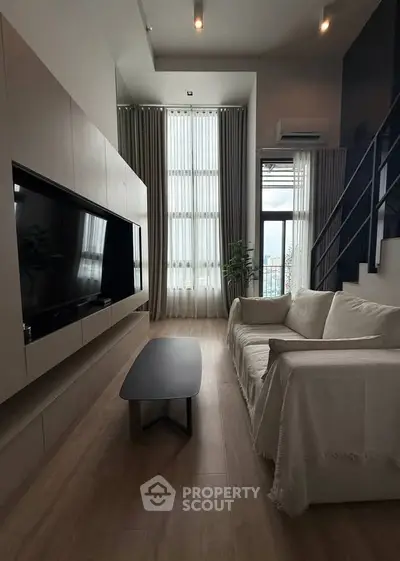 Modern living room with high ceilings, large windows, and stylish decor