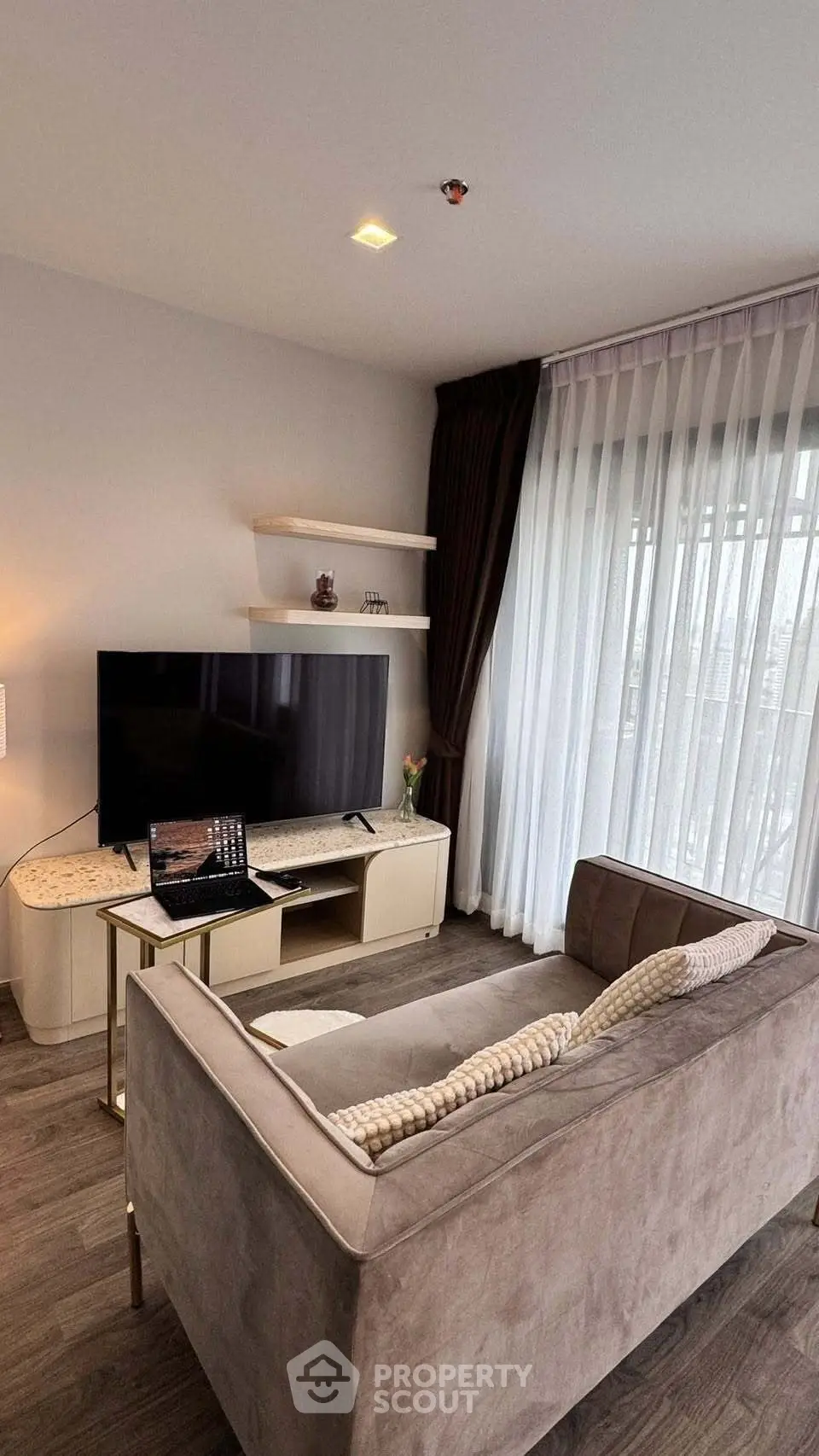 Modern living room with stylish decor and large TV, featuring elegant curtains and cozy seating.