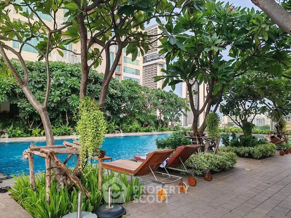 Luxurious poolside area with lush greenery and comfortable loungers in a modern residential complex.