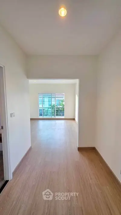 Spacious and bright living area with wooden flooring and large windows leading to a balcony.
