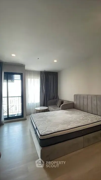 Spacious bedroom with modern decor and large window offering natural light.