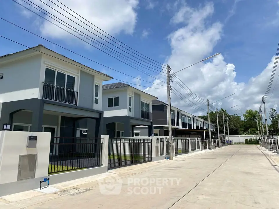 Modern townhouse development with clear blue skies and spacious driveways.