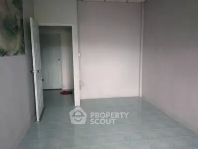 Spacious empty room with tiled floor and open door, ready for customization.