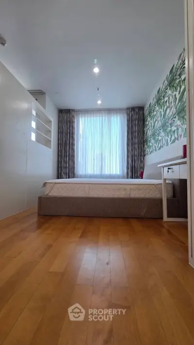 Spacious bedroom with modern decor and large window for natural light.