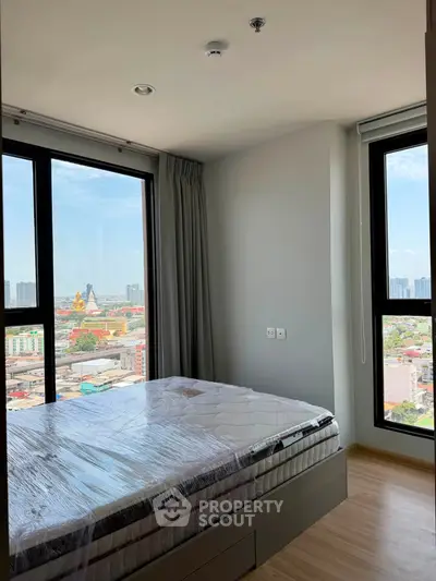 Modern bedroom with large windows offering stunning city views in a high-rise apartment.