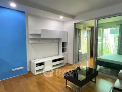 Modern living room with sleek furniture and glass sliding doors leading to a cozy bedroom.