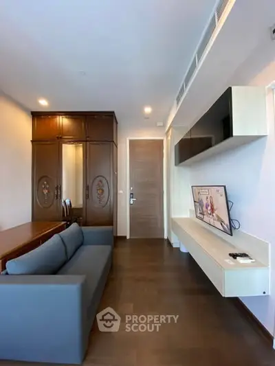 Modern living room with sleek furniture and wall-mounted TV in a stylish apartment.