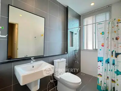 Modern bathroom with sleek fixtures and playful shower curtain in a contemporary home.