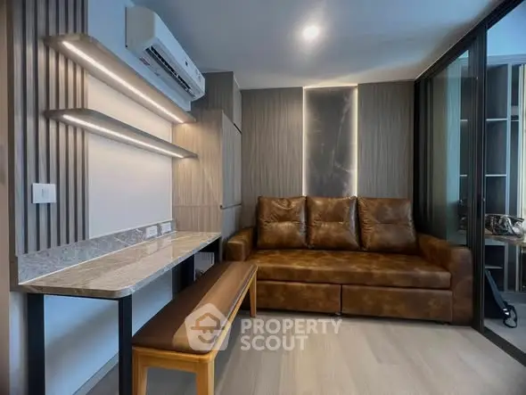 Modern living room with sleek design and leather sofa, featuring stylish lighting and a compact workspace.