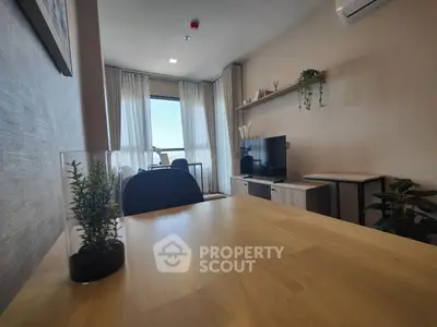 Modern living room with stylish decor and natural light, featuring a TV and dining area.