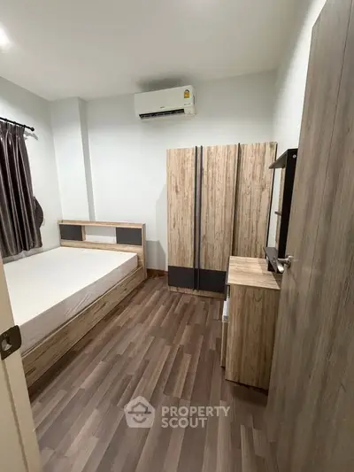 Modern bedroom with wooden flooring, stylish wardrobe, and air conditioning unit.