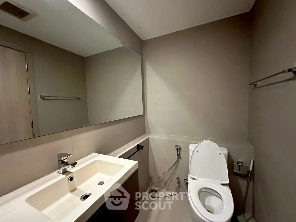 Modern bathroom with sleek fixtures and large mirror in a contemporary apartment.