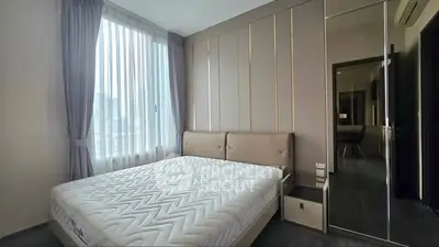 Modern bedroom with large window and stylish decor in a high-rise apartment.