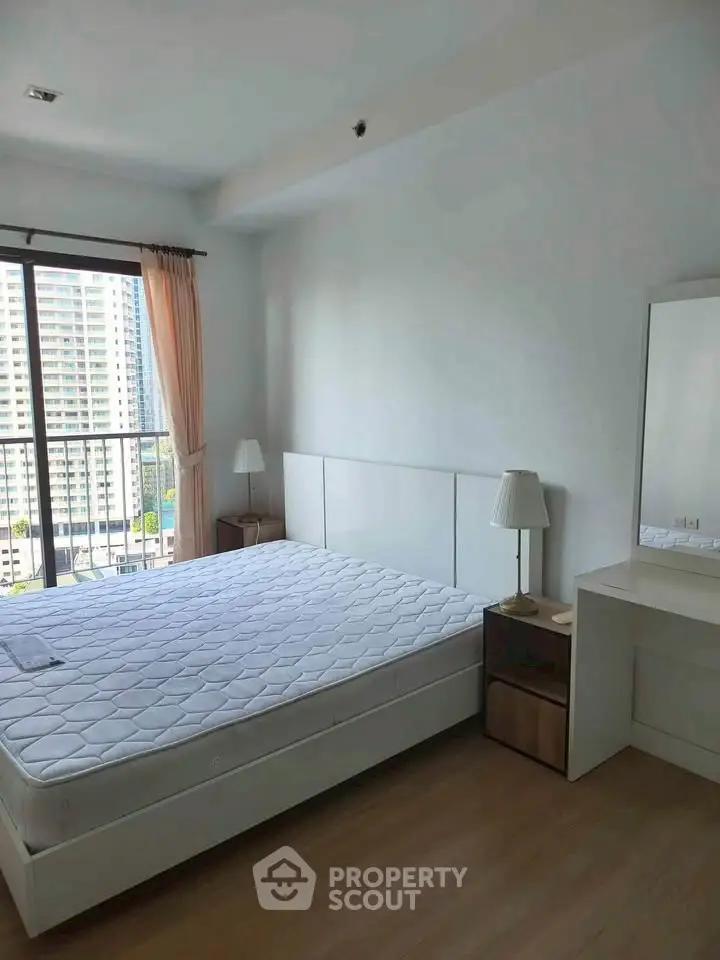 Bright bedroom with large window and city view, featuring a comfortable bed and stylish decor.