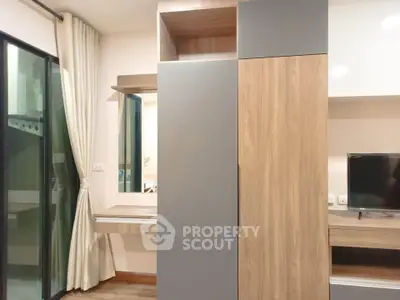Modern bedroom with sleek wooden wardrobe and TV unit, featuring a large window with elegant curtains.